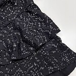 Close-up of a black dress adorned with intricate silver beadwork, perfect for formal occasions and evening wear.