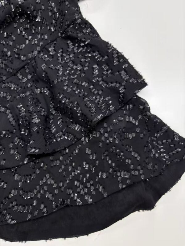 Close-up of a black dress adorned with intricate silver beadwork, perfect for formal occasions and evening wear.