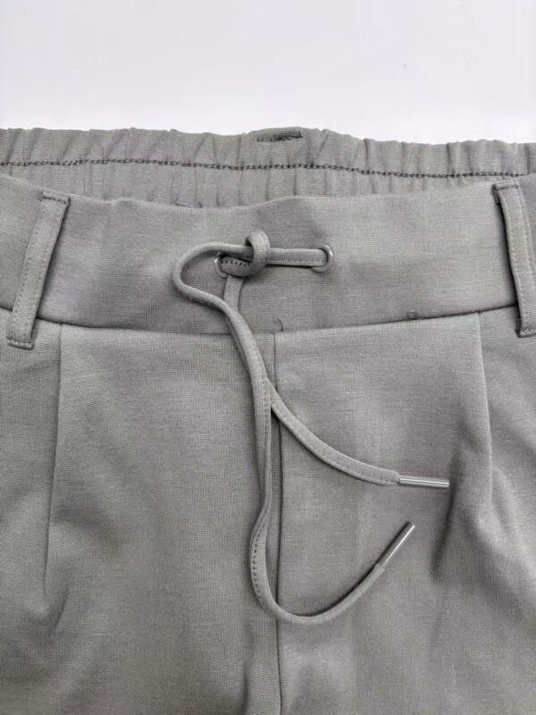 Close-up of grey men's pants with adjustable drawstring, suitable for casual or athletic wear, featuring a comfortable waistband and modern design.