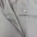 Close-up of a stylish grey dress shirt with silver buttons and a chest pocket, perfect for formal or business occasions.