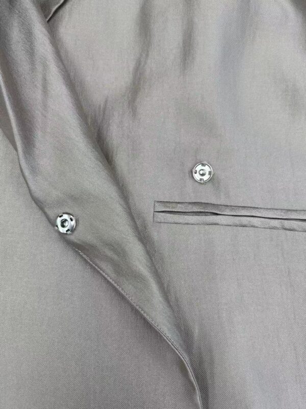 Close-up of a stylish grey dress shirt with silver buttons and a chest pocket, perfect for formal or business occasions.