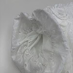 Close-up of a white lace hair bonnet with ruffled edges, ideal for hair protection and styling.