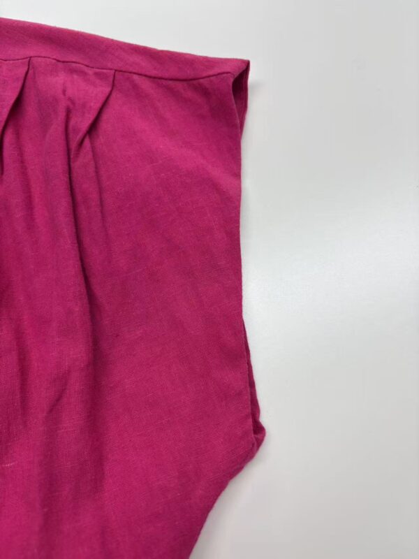 Close-up of vibrant pink velvet pants with pleats, showcasing soft texture and stylish design, perfect for fashionable women's wardrobe.