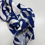 Stylish blue and white patterned scarf with a knot, perfect for adding a fashionable touch to any outfit.
