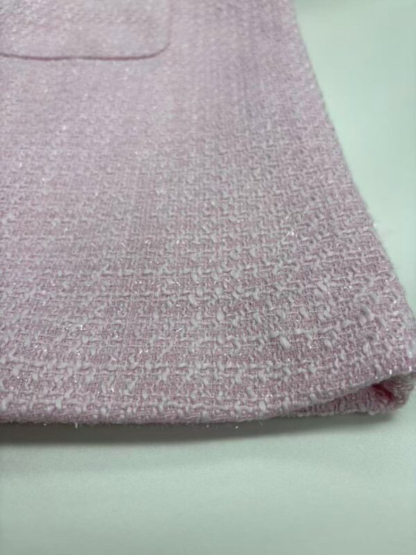 Close-up of pink textured fabric with a subtle shimmer, showcasing fine weave and luxurious appearance, ideal for fashion and upholstery.
