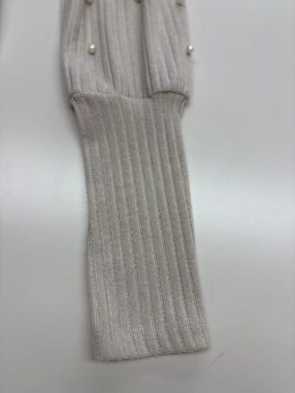 Close-up of a gray ribbed knit glove with pearl button details, showcasing high-quality craftsmanship and stylish design.