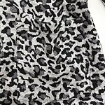 Close-up of leopard print fabric with black, gray, and white spots, showcasing a stylish animal print pattern for clothing or accessories.