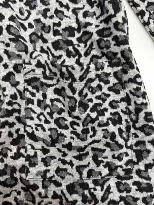 Close-up of leopard print fabric with black, gray, and white spots, showcasing a stylish animal print pattern for clothing or accessories.
