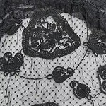 Close-up of black lace fabric with floral patterns and mesh background, ideal for stylish clothing and accessories.