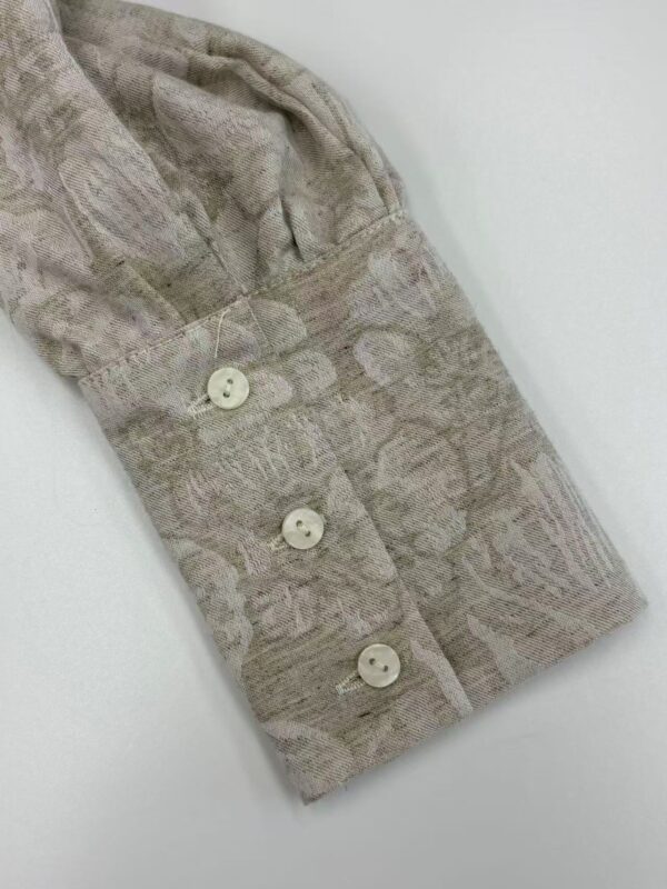 Close-up of a stylish women's shirt sleeve with a subtle pattern and four white buttons, showcasing high-quality fabric and craftsmanship.