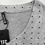 Close-up of a grey women's T-shirt with black polka dots, featuring a round neckline and a clothing tag from Chicoree, ideal for casual fashion.