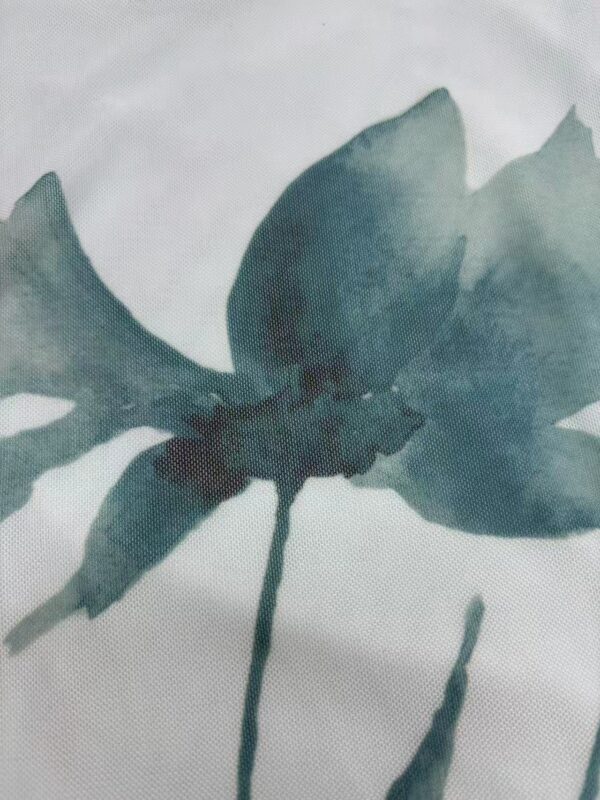 Close-up of a fabric with a watercolor butterfly design in shades of blue and teal, showcasing delicate artistic details.