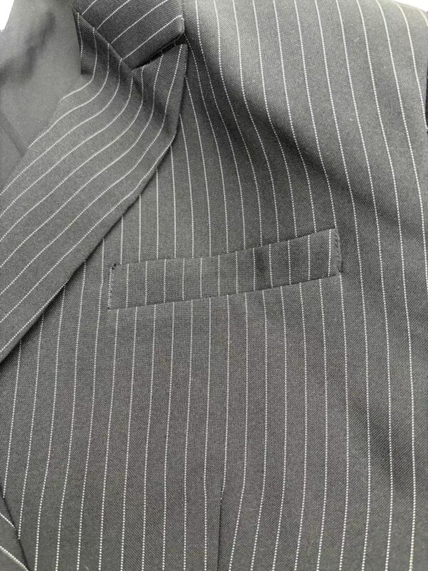 Close-up of a gray pinstripe suit jacket with a welt pocket, showcasing fine tailoring and classic design suitable for formal occasions.