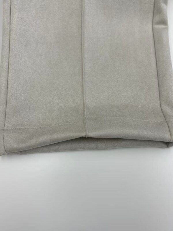 Close-up of beige fabric material showing smooth texture and stitching details, ideal for fashion and clothing design.