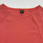 Close-up of a red textured women's blouse with a round neckline, featuring a subtle geometric pattern, suitable for casual or office wear.