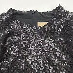 Close-up of a black dress covered in shiny sequins, perfect for evening wear or special occasions.