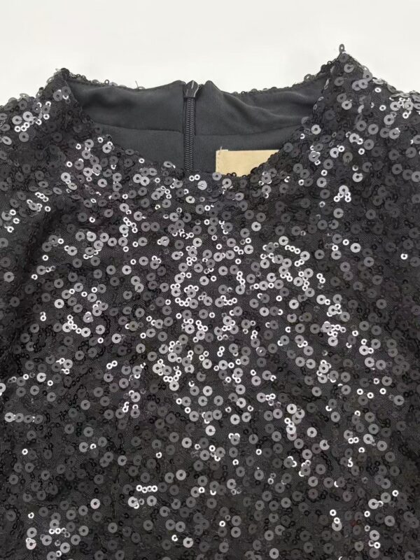 Close-up of a black dress covered in shiny sequins, perfect for evening wear or special occasions.