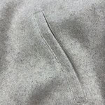 Detailed close-up of grey fabric with a visible stitched seam, highlighting the texture and quality of the material, suitable for fashion and clothing product images.