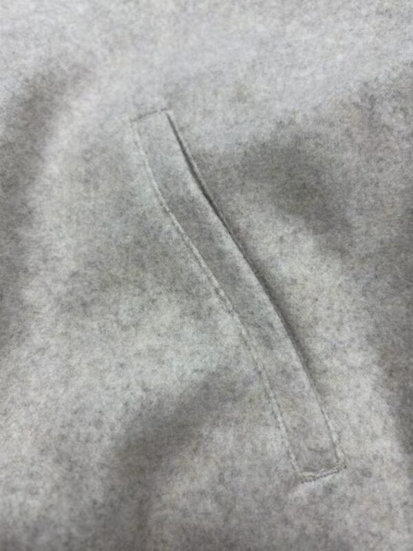 Detailed close-up of grey fabric with a visible stitched seam, highlighting the texture and quality of the material, suitable for fashion and clothing product images.