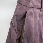 Close-up of stylish mauve women's trousers with pleats and side zipper detail, perfect for office or casual wear.