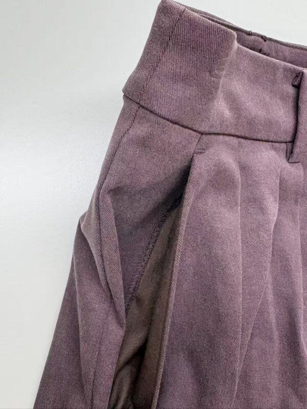 Close-up of stylish mauve women's trousers with pleats and side zipper detail, perfect for office or casual wear.