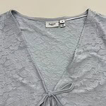 Close-up of a light gray lace dress with a V-neckline and bow detail, perfect for stylish occasions.