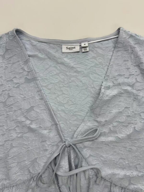 Close-up of a light gray lace dress with a V-neckline and bow detail, perfect for stylish occasions.