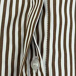 Close-up of a brown and white vertically striped shirt with a white button and zipper detail, showcasing stylish casual fashion.
