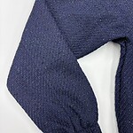 Close-up of a navy blue knitted sweater sleeve with textured fabric and elastic cuff, perfect for fall and winter fashion.
