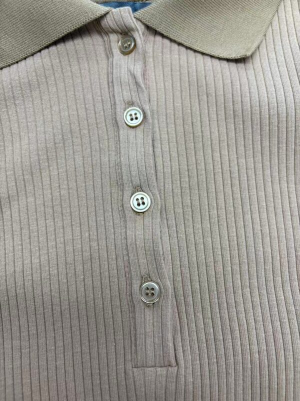 Close-up of a beige ribbed polo shirt with a collar and four buttons, showcasing a classic and stylish design suitable for casual or semi-formal wear.