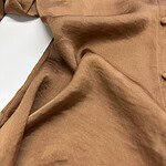 Close-up of a luxurious brown satin dress with smooth texture and subtle sheen, showcasing elegant fabric draping and craftsmanship.
