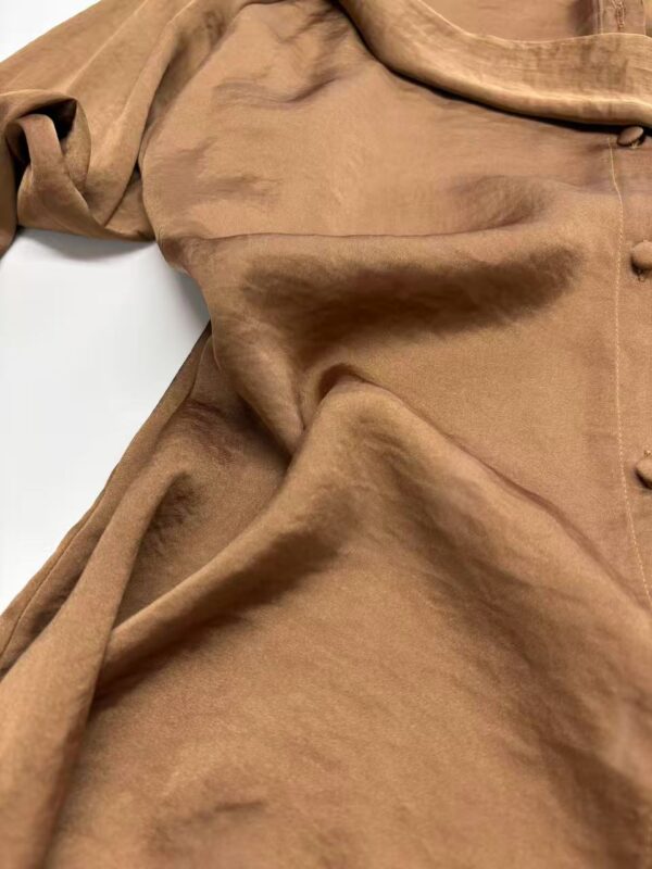 Close-up of a luxurious brown satin dress with smooth texture and subtle sheen, showcasing elegant fabric draping and craftsmanship.