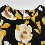 Close-up of a women's dress with a vibrant floral pattern in yellow, white, and black colors, perfect for spring and summer fashion.