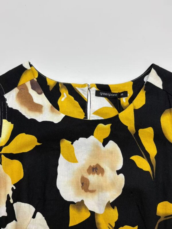 Close-up of a women's dress with a vibrant floral pattern in yellow, white, and black colors, perfect for spring and summer fashion.