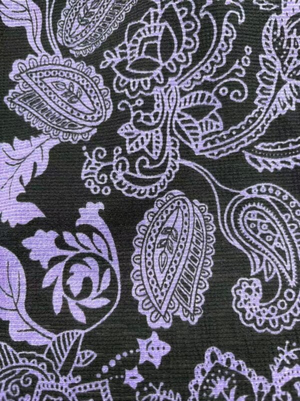 Close-up of a black fabric with intricate purple paisley and floral patterns, ideal for stylish clothing and accessories.