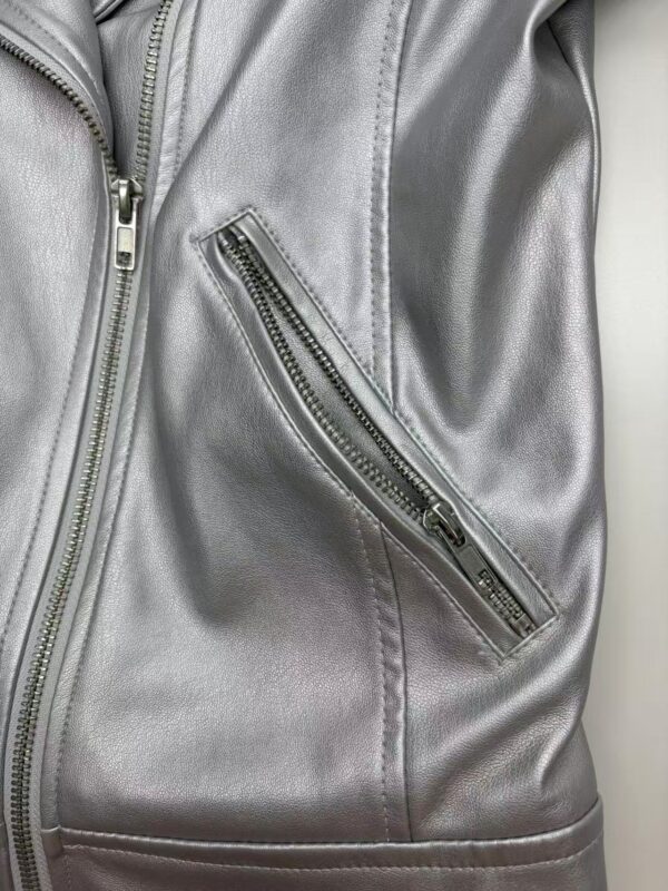 Close-up of a silver leather jacket featuring a diagonal zippered pocket, showcasing modern fashion and high-quality material.