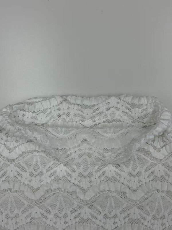 Close-up of intricate white lace fabric with floral and geometric patterns, ideal for fashion and dressmaking.