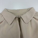 Close-up of a beige women's jacket with a collar and zipper, showcasing a stylish and casual fashion piece.