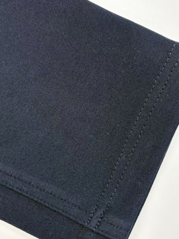 Detailed close-up of black fabric with visible texture and stitching, suitable for fashion or textile product images.
