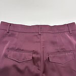 Close-up of burgundy women's dress pants with back pockets, tailored fit, and belt loops, perfect for office or formal occasions.