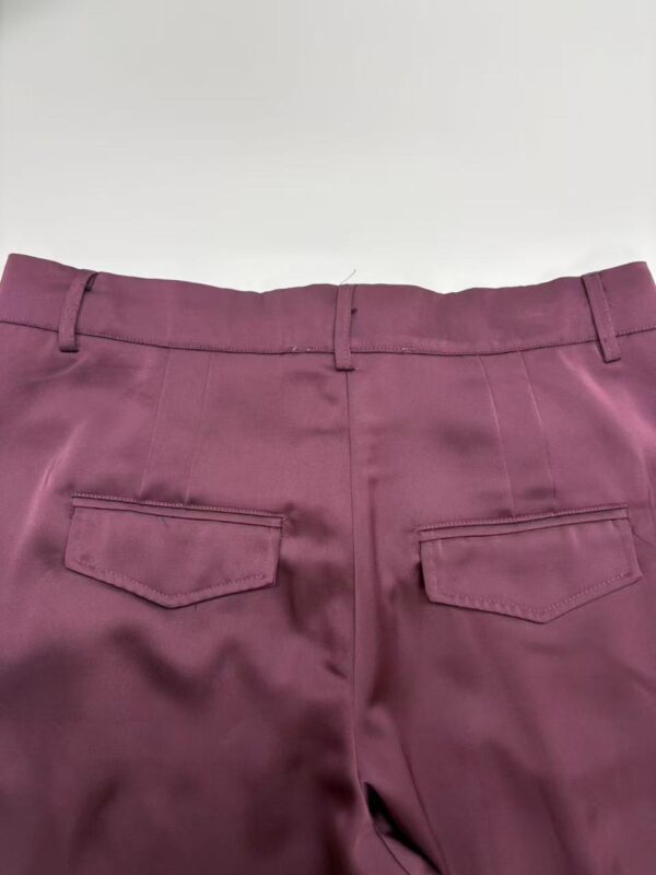 Close-up of burgundy women's dress pants with back pockets, tailored fit, and belt loops, perfect for office or formal occasions.