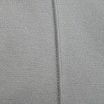 Detailed close-up of grey fabric showing fine woven texture and a central seam, ideal for fashion or textile product images.