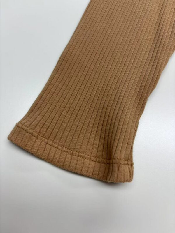 Close-up of a brown ribbed knit sweater sleeve with detailed stitching and texture, showcasing high-quality fabric and craftsmanship.
