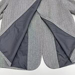 Close-up of a men's grey suit jacket with black lining, showcasing the fabric and tailoring details for professional or formal occasions.