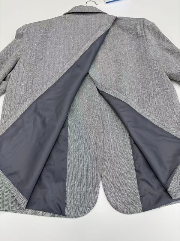 Close-up of a men's grey suit jacket with black lining, showcasing the fabric and tailoring details for professional or formal occasions.