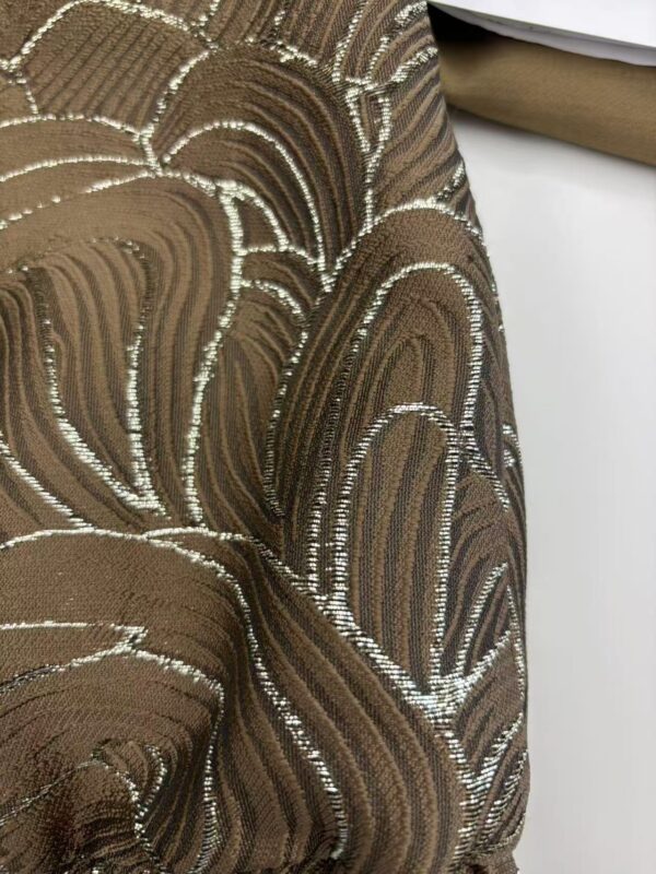 Close-up of luxurious brown fabric with intricate silver embroidery, perfect for high-end fashion or interior decor.