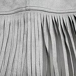 Close-up of gray leather with long, thin fringes, showcasing texture and craftsmanship for fashion accessories or clothing.