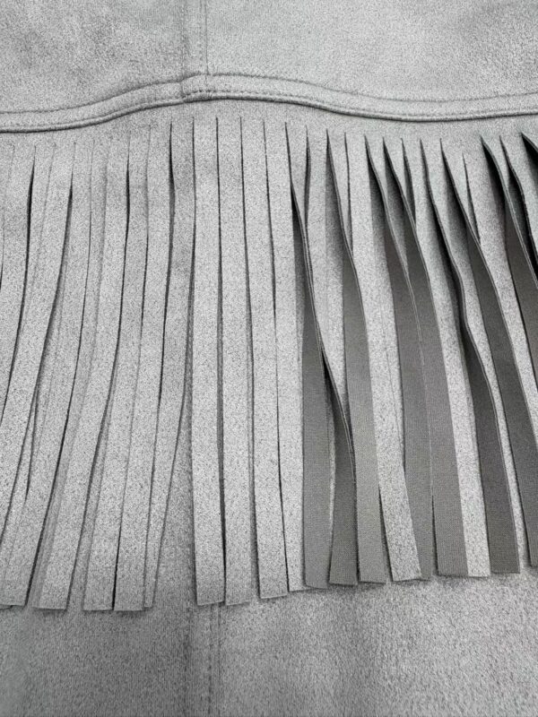 Close-up of gray leather with long, thin fringes, showcasing texture and craftsmanship for fashion accessories or clothing.