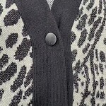 Close-up of a leopard print cardigan featuring a black trim and a single black button, showcasing stylish and trendy fashion details.