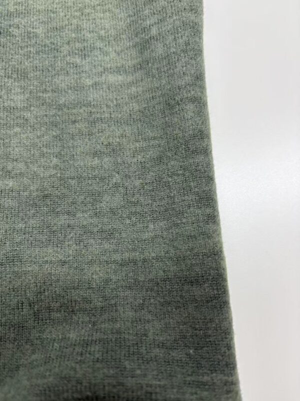 Close-up of green fabric textile material suitable for fashion and apparel design, showing detailed texture and weave pattern.